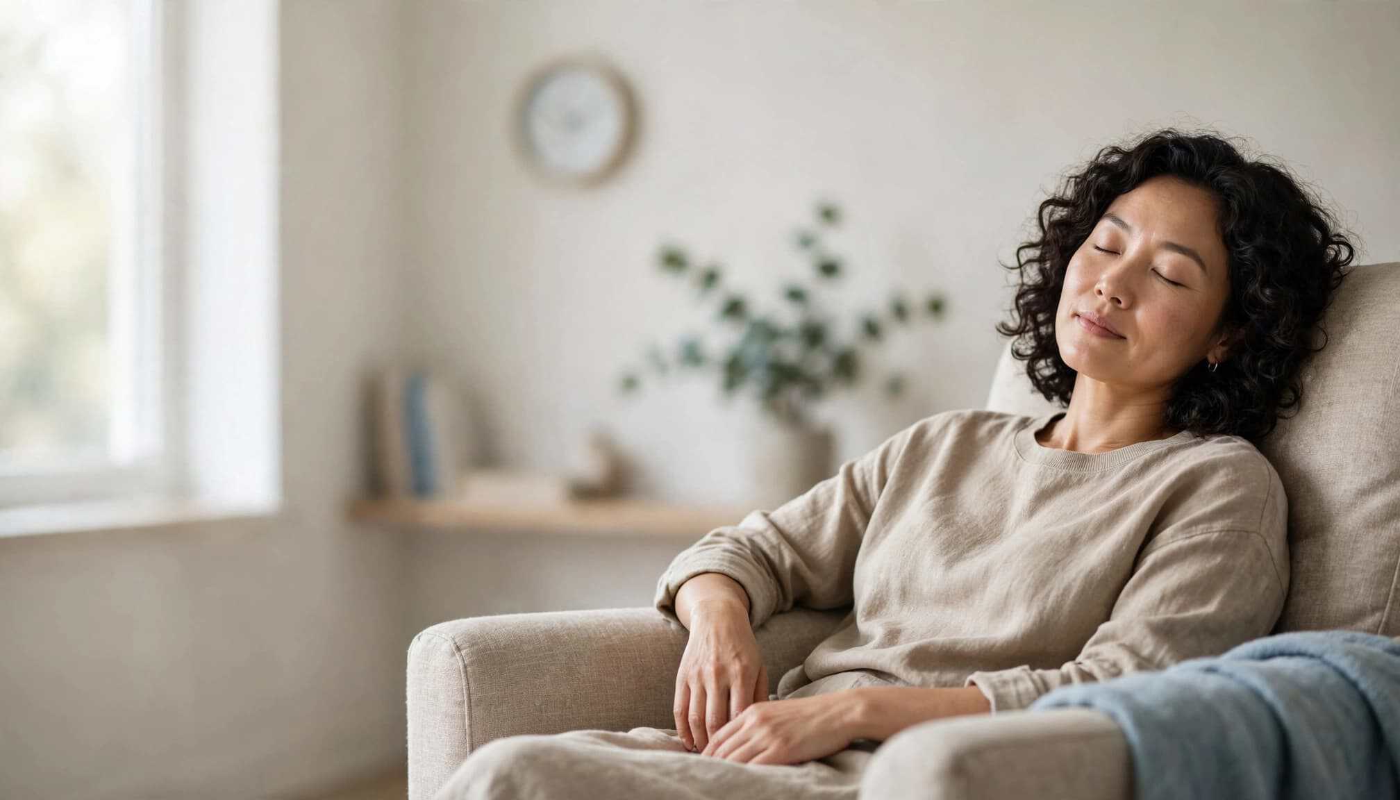 Adult resting with closed eyes in an armchair in a bright reading nook.
